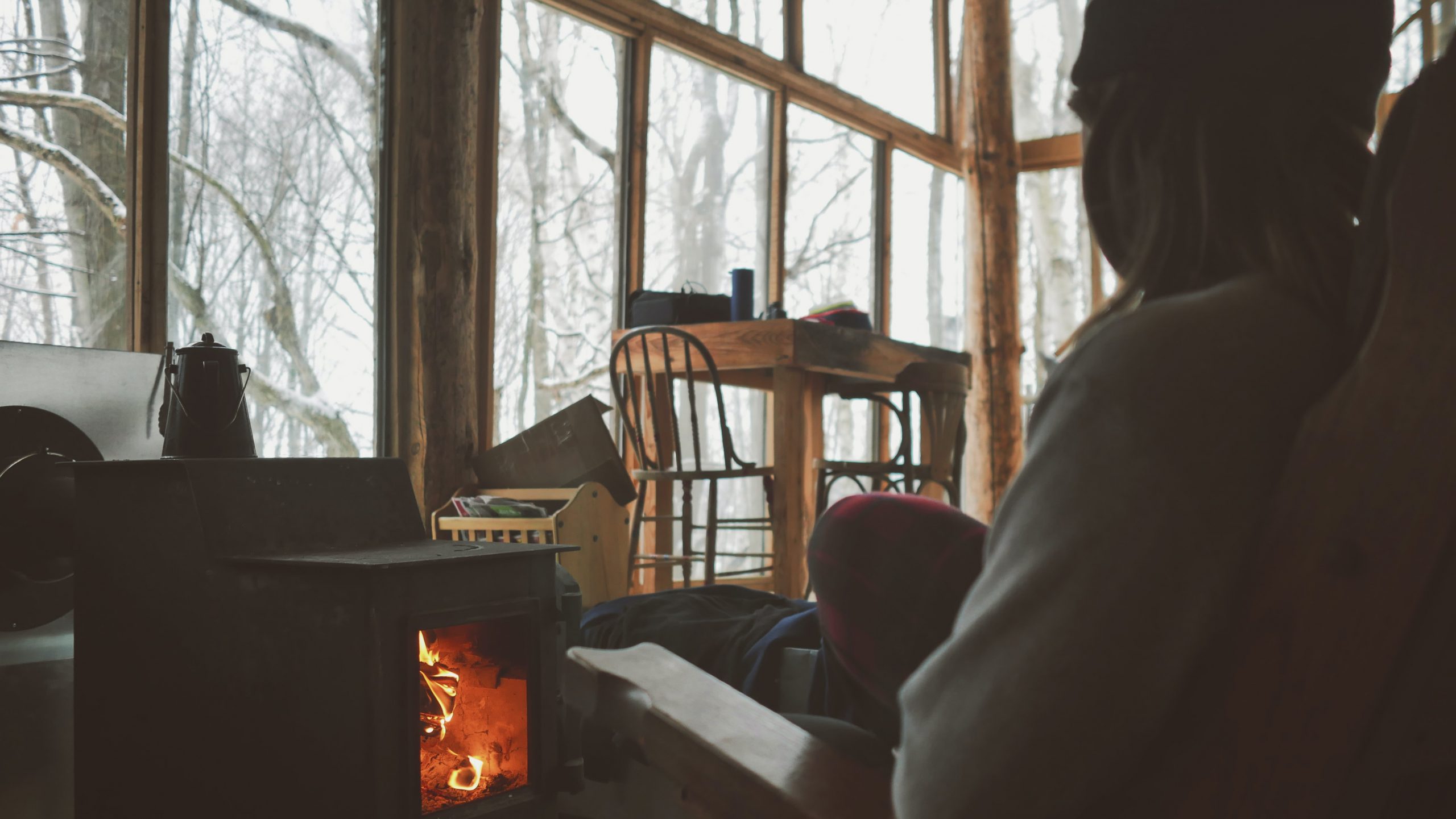 man warming up by woodstove